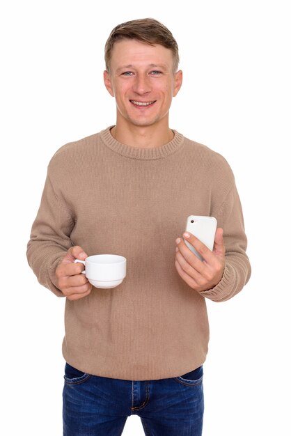 joven feliz sosteniendo un teléfono móvil y una taza de té