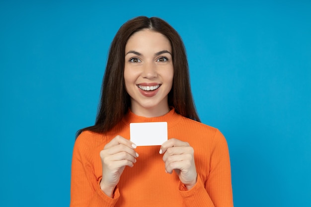 Foto joven feliz con una tarjeta en la mano sobre un fondo azul