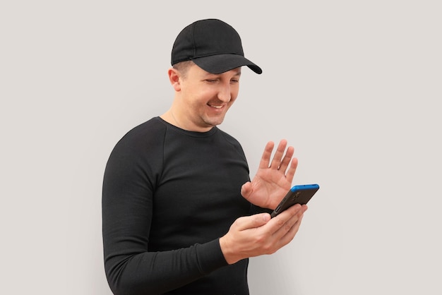 Foto un joven feliz usa un teléfono móvil con un fondo gris