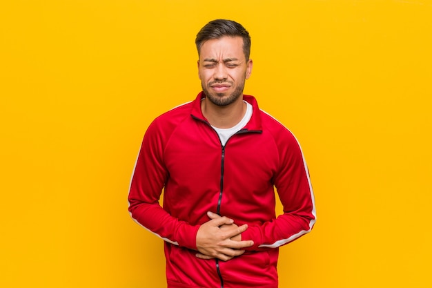 Joven filipino fitness hombre enfermo, que sufre de dolor de estómago, concepto de enfermedad dolorosa.