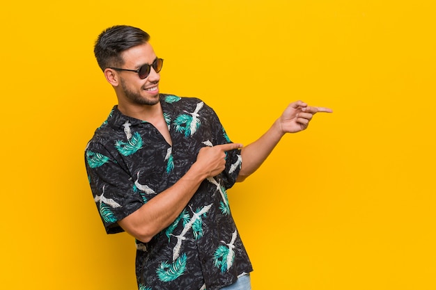 Joven filipino hombre vestido con ropa de verano excitado señalando con los dedos lejos.