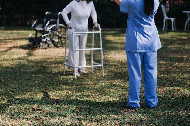 Joven fisioterapeuta asiático trabajando con una mujer mayor en caminar con un andador