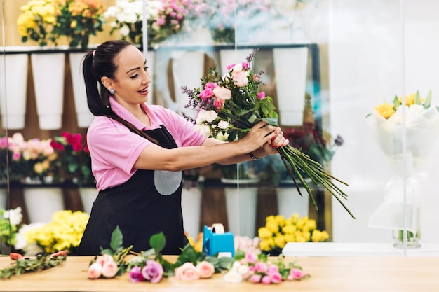 Foto una joven florista atractiva trabaja en una floristería y hace arreglos florales para la venta