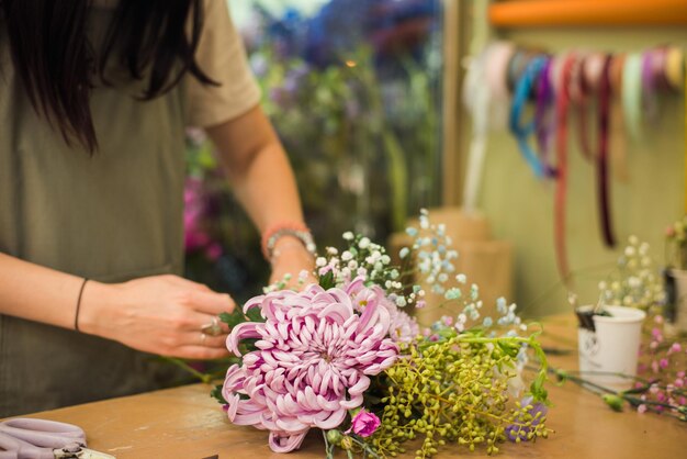 Joven florista haciendo ramos de flores frescas negocio de floristería sin rostro