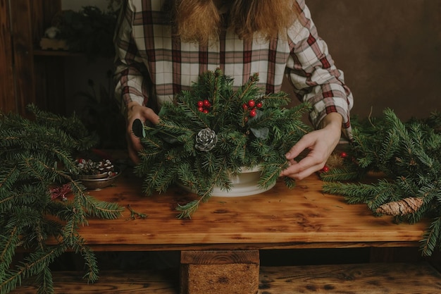 Joven floristería creando un arreglo floral de Navidad en un estudio de floristería