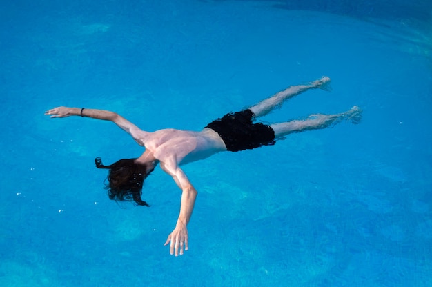 Joven flotando y divirtiéndose en la piscina