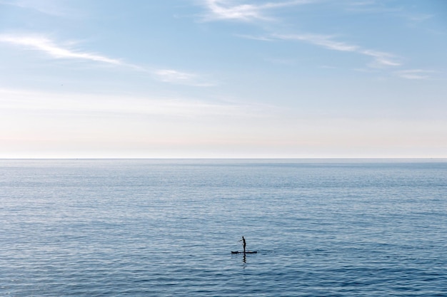 Joven flotando en una tabla de SUP La aventura del mar con agua azul en un surf