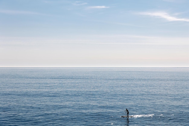 Joven flotando en una tabla de SUP La aventura del mar con agua azul en un surf