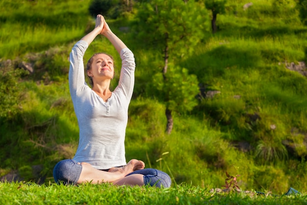 Joven en forma deportiva haciendo yoga Lotus pose oudoors