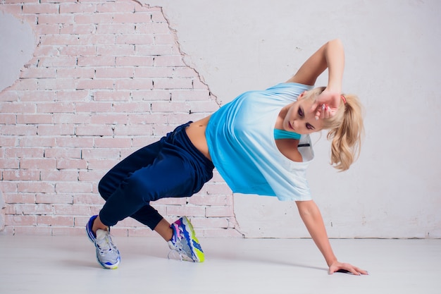 Joven, en forma y deportiva mujer de pie delante de la pared de cemento de hormigón