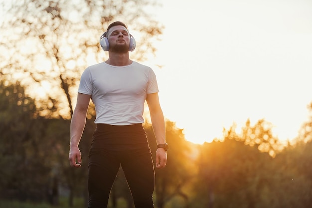 Foto joven en forma con los ojos cerrados en ropa deportiva escuchando música mientras descansa después de correr o hacer ejercicio