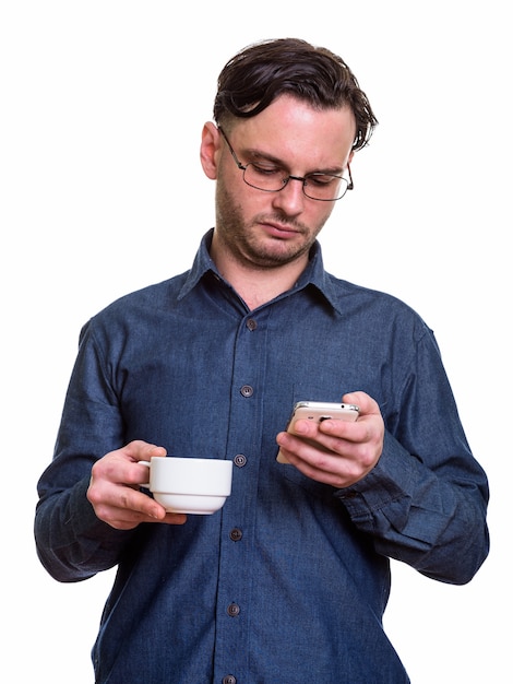 joven formal mediante teléfono móvil mientras sostiene la taza de café