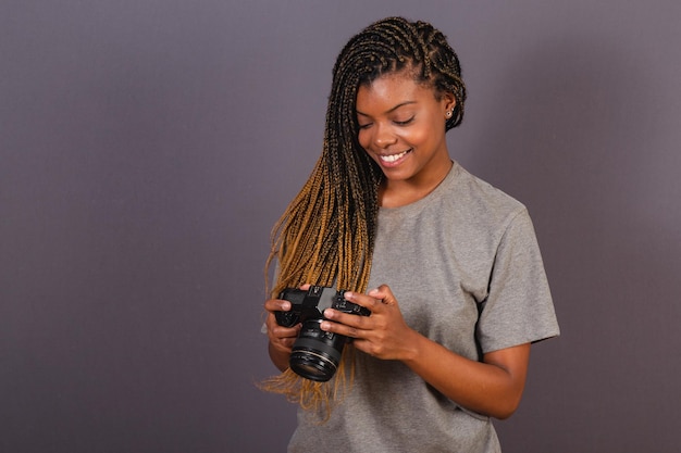 Joven fotógrafa afro brasileña sonriendo sosteniendo una cámara de fotos