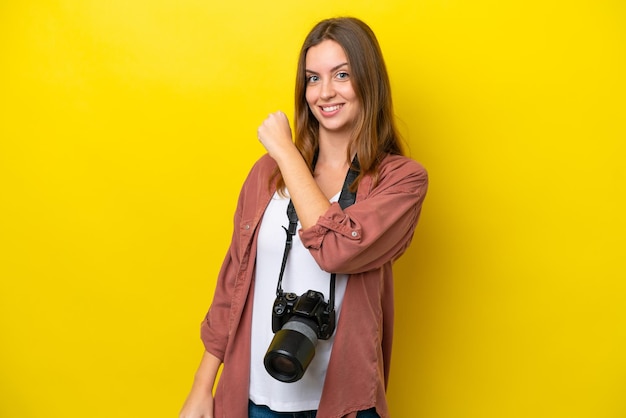 Joven fotógrafa caucásica aislada de fondo amarillo celebrando una victoria