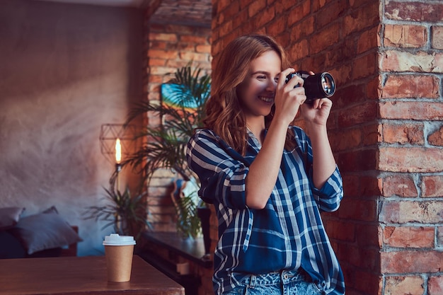 Joven fotógrafa encantadora se encuentra en una habitación con un loft en