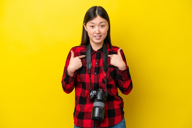 Joven fotógrafa mujer china aislada de fondo amarillo con expresión facial sorpresa