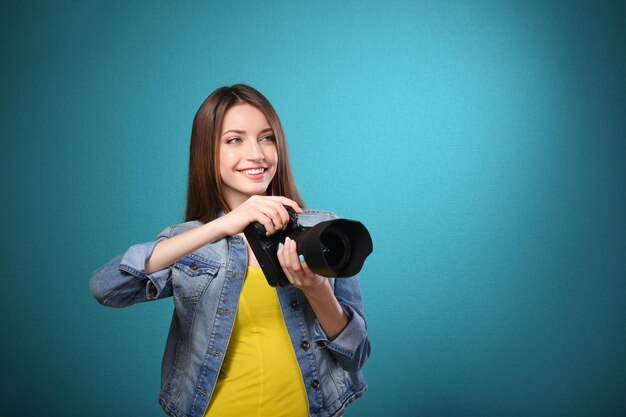 Joven fotógrafa tomando fotos con fondo azul