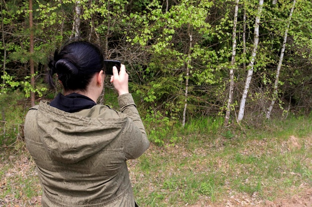 Una joven fotografía la hermosa naturaleza en un parque a principios de la primavera en un teléfono inteligente El concepto de turismo kaiking pasión por la naturaleza y la fotografía