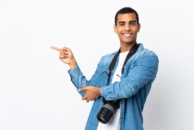 Joven fotógrafo afroamericano hombre sobre pared blanca aislada apuntando con el dedo al lado