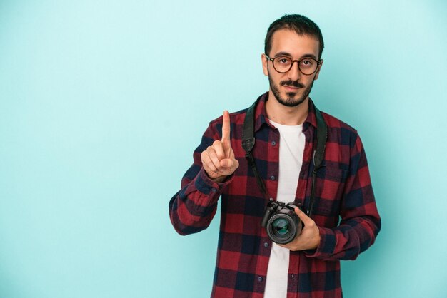 Foto joven fotógrafo caucásico aislado de fondo azul que muestra el número uno con el dedo