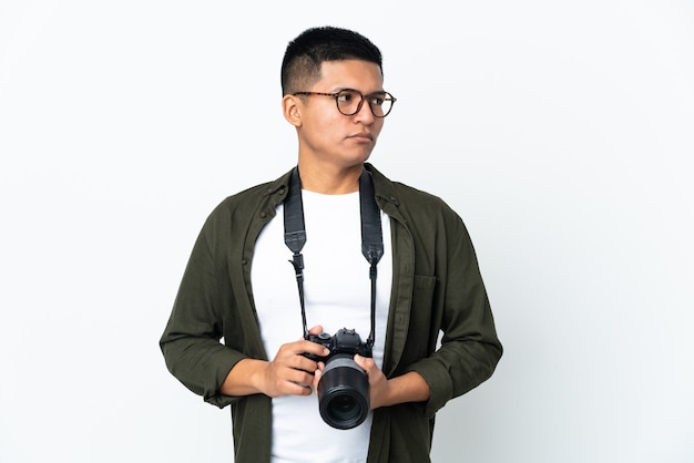Joven fotógrafo ecuatoriano aislado en una pared blanca mirando hacia el lado
