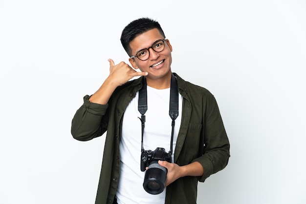 Joven fotógrafo ecuatoriano aislado sobre fondo blanco haciendo gesto de teléfono. Llámame señal