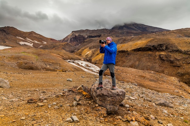 Joven fotógrafo en el fondo de rocas volcánicas Kamchatka