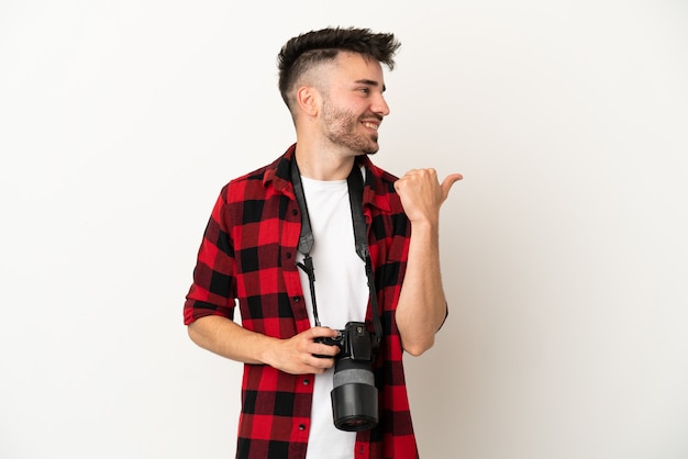 Joven fotógrafo hombre caucásico aislado sobre fondo blanco apuntando hacia el lado para presentar un producto