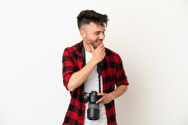 Joven fotógrafo hombre caucásico aislado sobre fondo blanco mirando hacia el lado