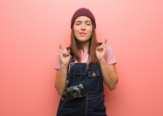 Joven fotógrafo lindo mujer cruzando los dedos para tener suerte