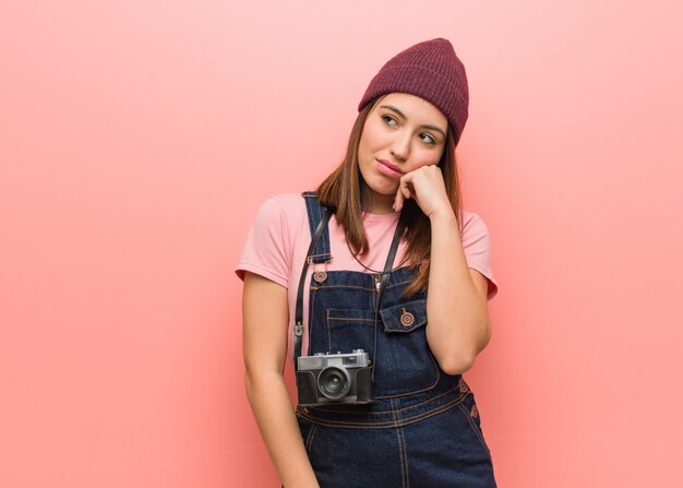 Joven fotógrafo lindo mujer pensando en algo, mirando hacia un lado