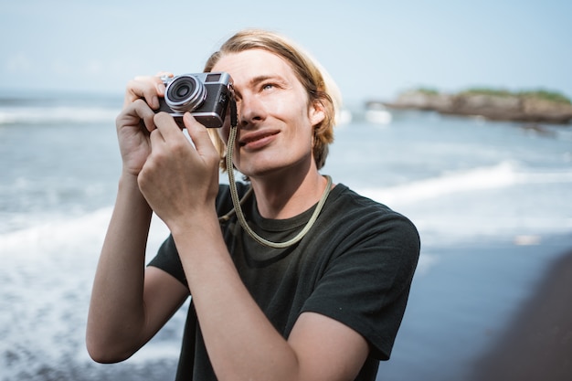 Joven fotógrafo masculino guapo en la playa