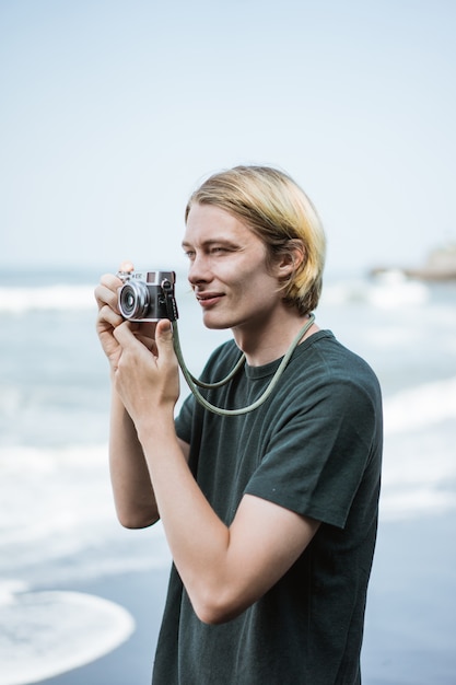 Joven fotógrafo masculino guapo en la playa