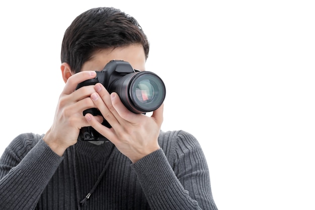 Joven fotógrafo profesional exitoso en camisa utiliza cámara digital DSLR aislado sobre fondo blanco.