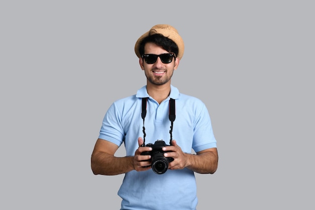 joven fotógrafo sonriendo y sosteniendo la cámara modelo pakistaní indio