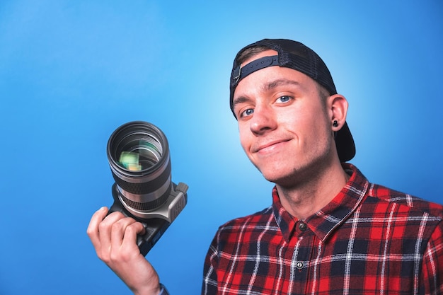 Un joven fotógrafo sonriente y feliz tomando fotos comprobando las configuraciones de su cámara en un rodaje de estudio