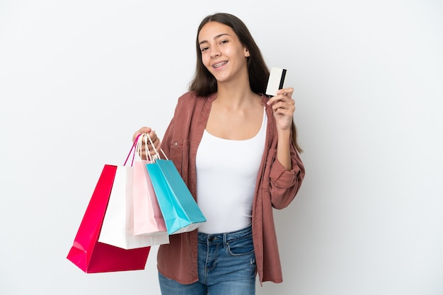 Joven francesa aislada sobre fondo blanco sosteniendo bolsas de la compra y una tarjeta de crédito