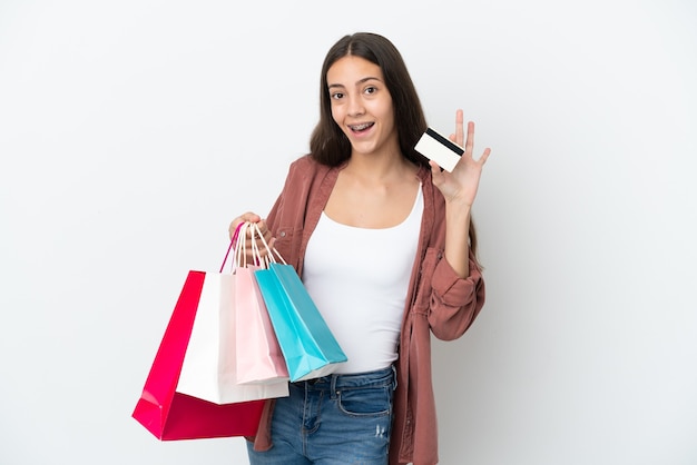 Joven francesa aislada sobre fondo blanco sosteniendo bolsas de la compra y una tarjeta de crédito