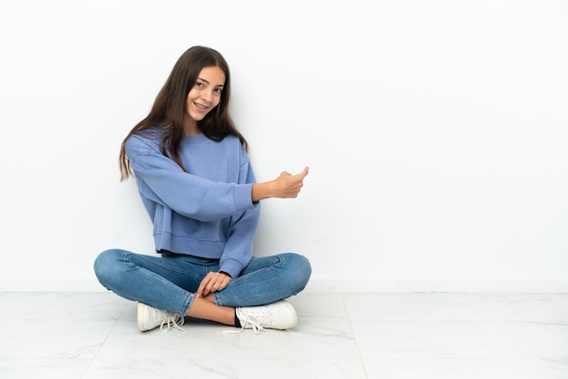 Joven francesa sentada en el suelo apuntando hacia atrás