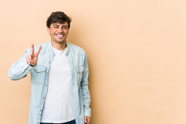 Joven fresco mostrando el signo de la victoria y sonriendo ampliamente