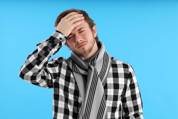 Joven con frío sobre fondo azul.