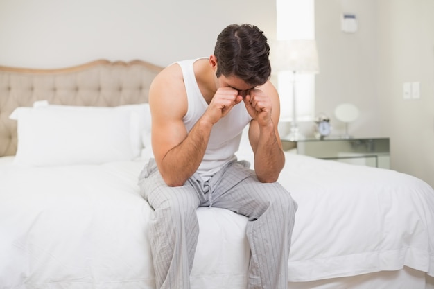 Joven frotando sus ojos en la cama