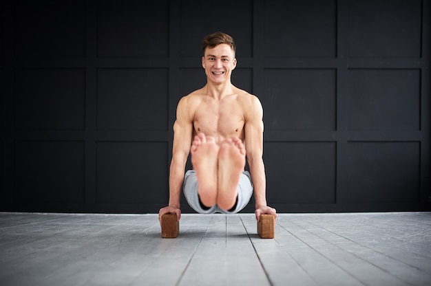 Joven fuerte sin camisa practica yoga en el estudio de yoga