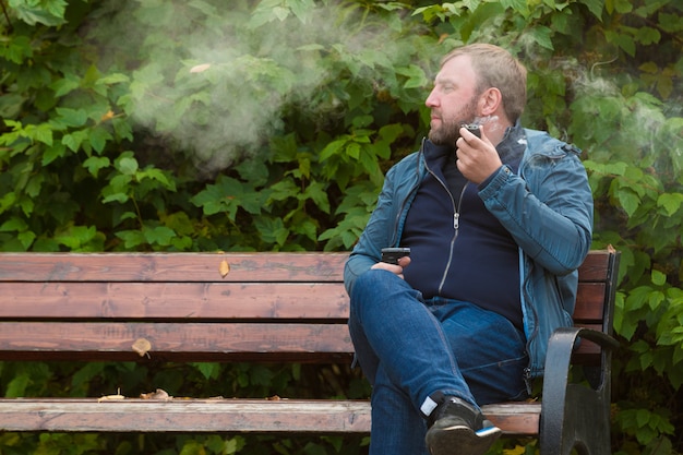 Joven fuma pipa de tabaco en el parque