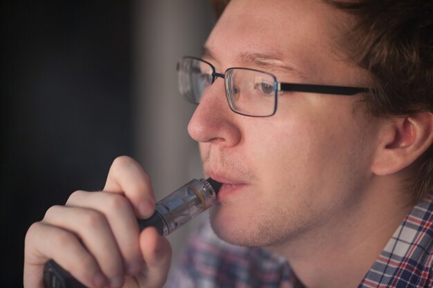 Joven fumando cigarrillo electrónico.