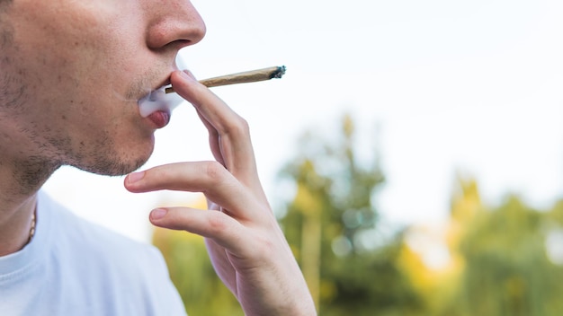 El joven fumando marihuana medicinal al aire libre El joven fuma cannabis contundente