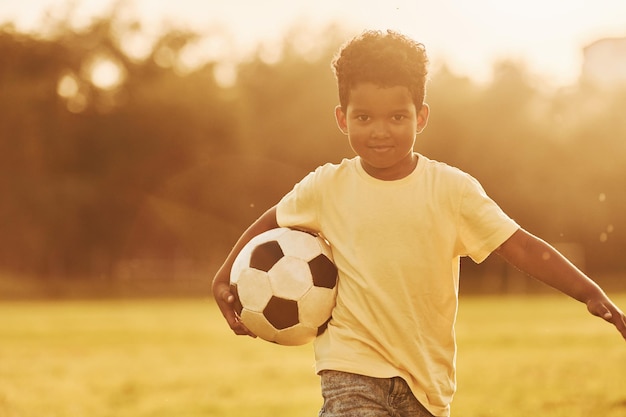 Un joven futbolista afroamericano se divierte en el campo durante el día de verano