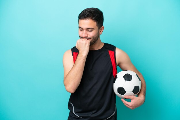 Joven futbolista brasileño aislado de fondo azul con dudas