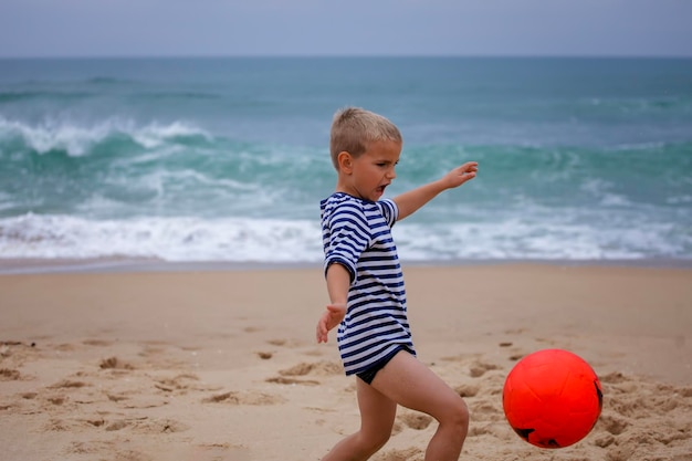 Foto joven futbolista juega descalzo en la orilla del océano fútbol deporte pasión estilo de vida activo