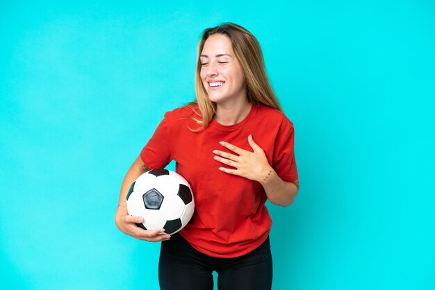 Joven futbolista mujer aislada de fondo azul sonriendo mucho